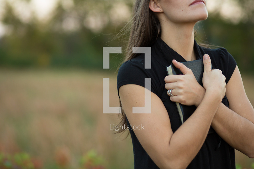 Stock Photo Woman clutching bible close to heart by Ryan Klintworth